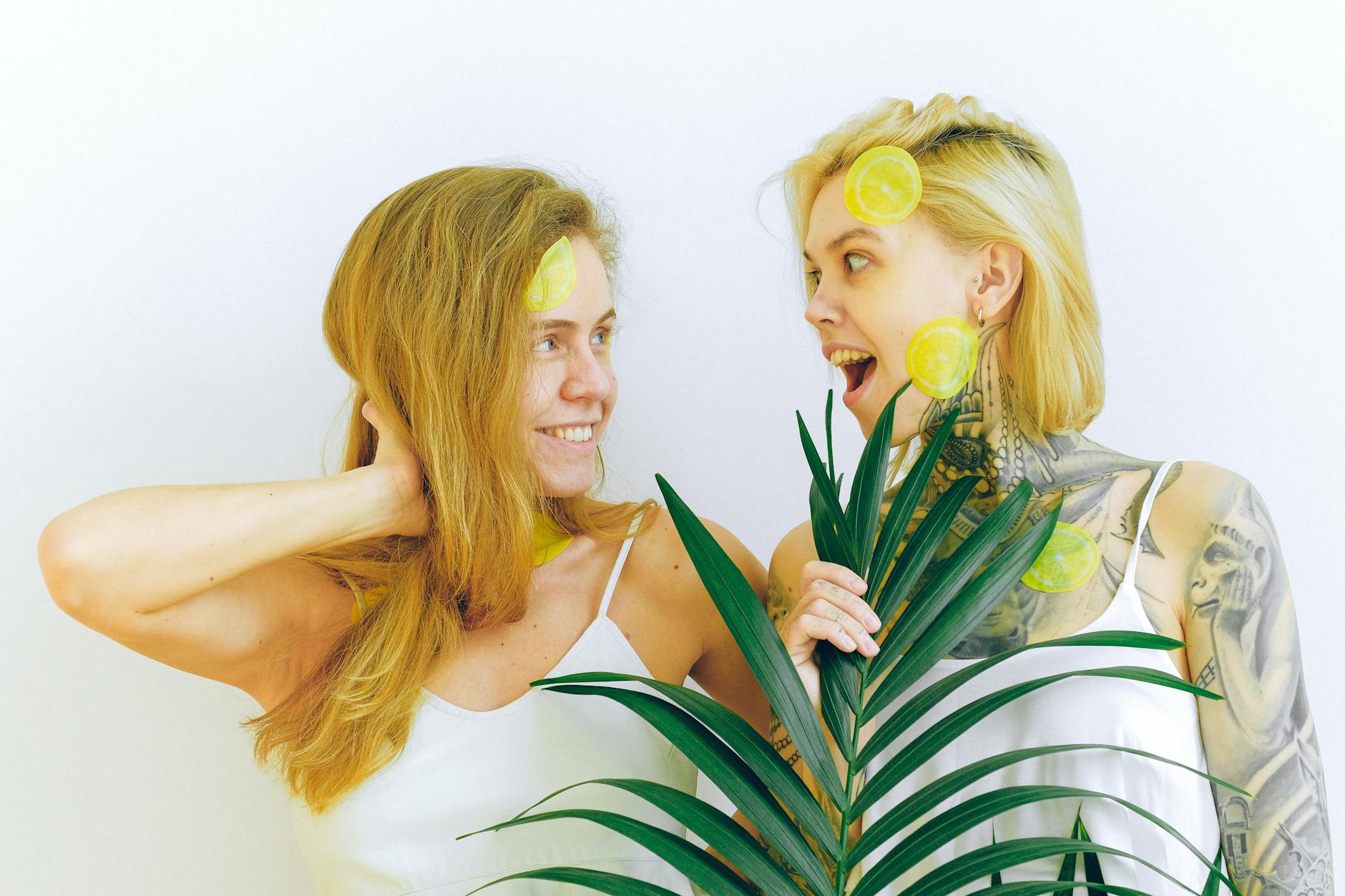 Two people smiling together with tropical plants, expressing joy and intimacy indoors
