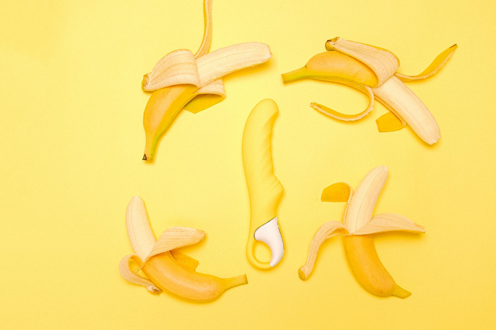 Yellow lemon clitoral vibrator surrounded by fresh lemons on a yellow background